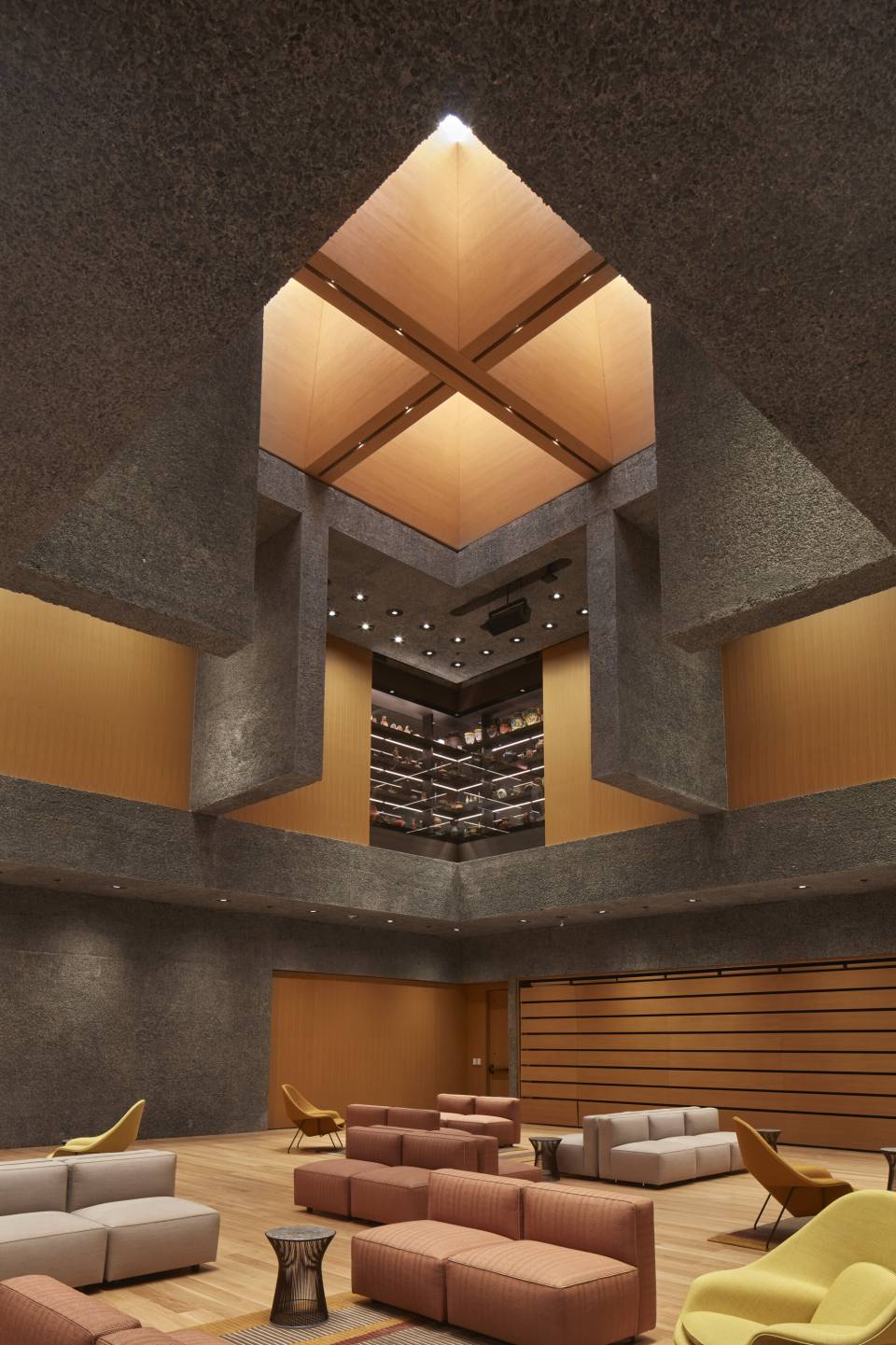 Dramatic quad skylight opens down onto a lounge of modern seating and woodgrain walls in the Grand Hall of the Princeton University Art Museum