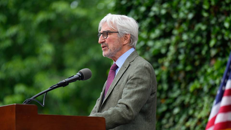 Sam Waterson speaking outdoors behind a podium