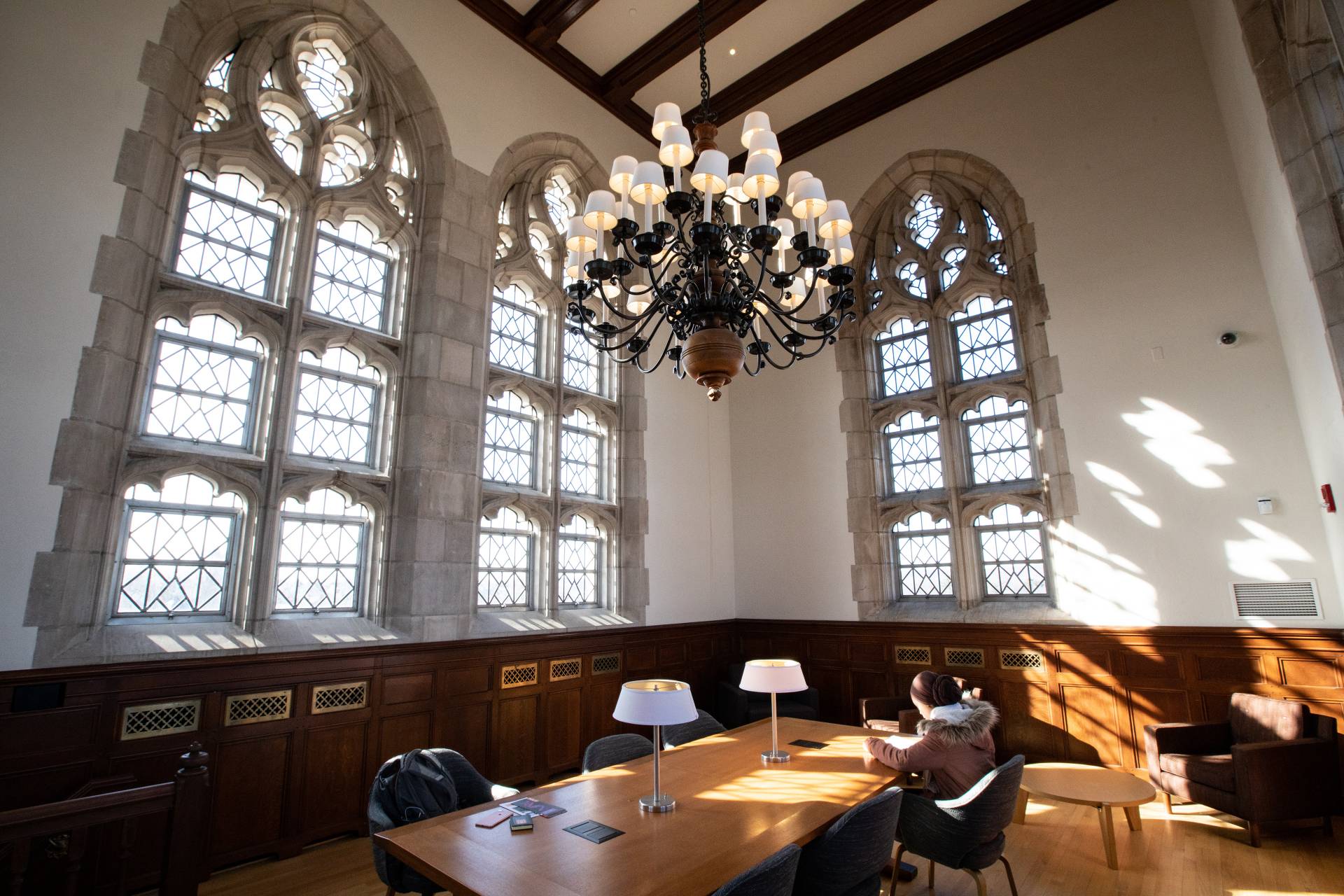 Student studying in room with large high windows and chandeliers