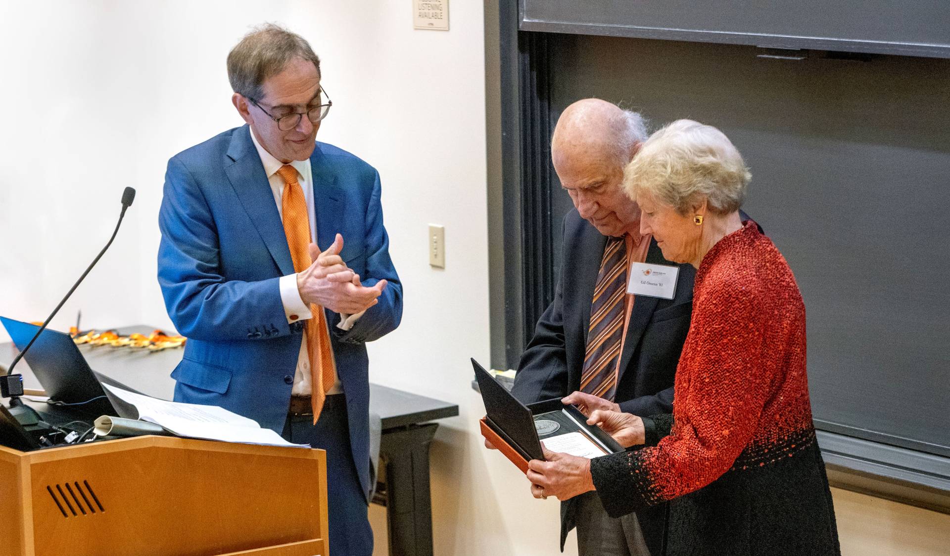 Christopher Eisgruber presents a plaque to Gil Omenn and Martha Darling